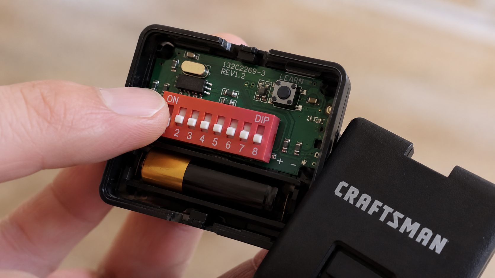 A close-up view of a Craftsman garage door remote control with the internal DIP switches exposed.